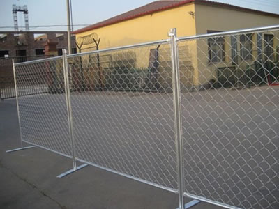 Galvanized chain link temporary fence stands on the ground of the factory.
