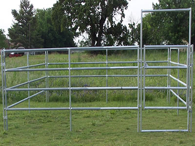 The galvanized corral panel with a gate stands on the lawn. The gate is installed with the fence panels with clamps.