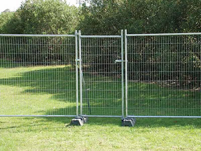 The pedestrian temporary fence gate is installed with the temporary fence panels in a greenbelt.