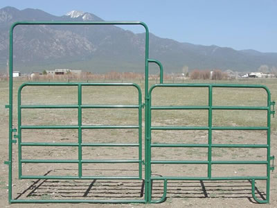 A green PVC coated corral panel gate stands on the ground. The gate frame is welded onto the panel.