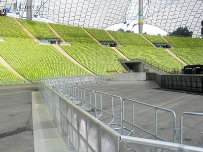Two long rows of stage barriers parallel to police barrier, they serve as a barricade together in sport venue.