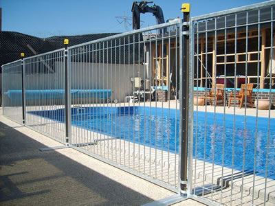 A galvanized temporary pool fencing with flat metal feet is installed at public swimming pool.