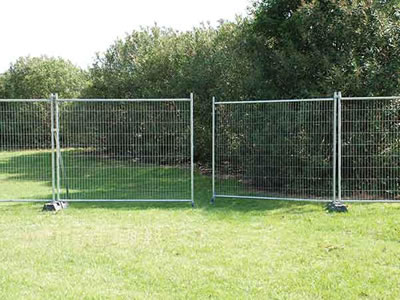 A double leafs temporary fence gate installs with temporary fence panel in a greenbelt.