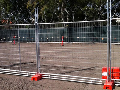 Two dog bars on the galvanized welded temporary fence, the fence is installed with the plastic moulded feet and barbed wire.
