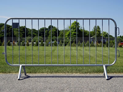 A barricade fence panel with crossed feet stands on the concrete.