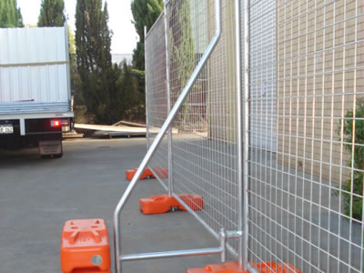 A steel temporary fence bracing supports the temporary fence with three orange plastic moulded feet installed.
