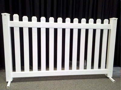 A white picket event fencing panel on concrete.