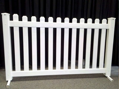 A white picket event fencing panel on concrete.